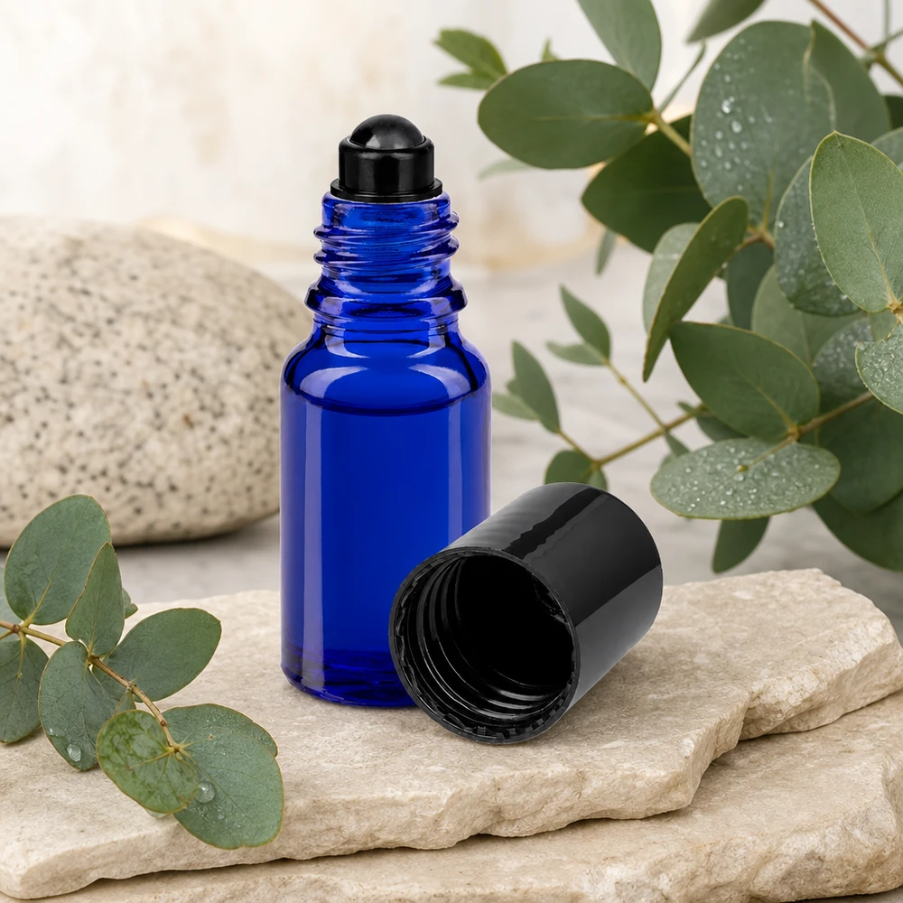 Apothekenflasche blau 10ml Roll-On Verschluss schwarz Blaue 10ml Rollerflasche aus ApoGlas mit schwarzer Rollkugel auf Naturstein vor botanischem Hintergrund