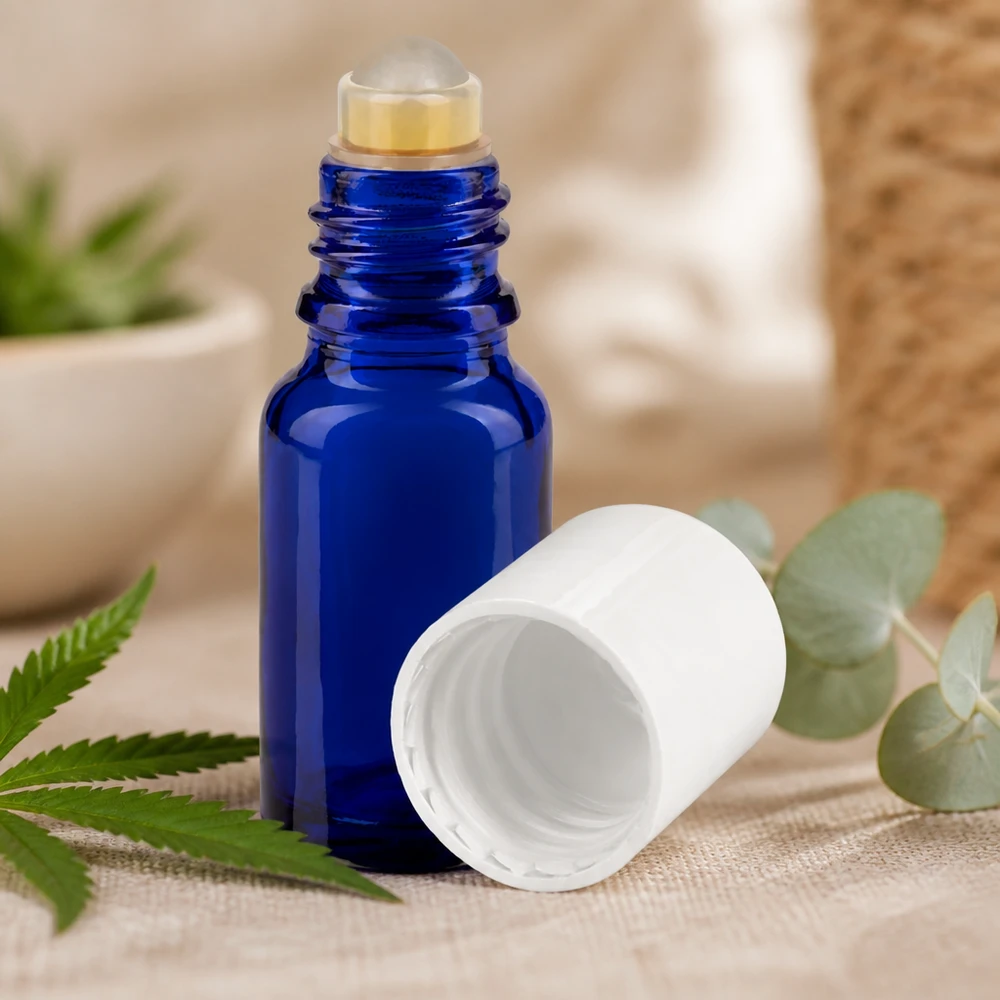 Kompakte blaue Apothekerglasfl asche mit Rollapplikator zwischen frischen grünen Pflanzenblättern