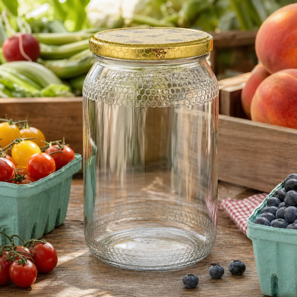 1260g Honigglas + BasicSeal Deckel Bienenwabe UNiTWIST 900ml Honigglas leer mit goldenem Bienenwaben-Deckel zwischen frischem Obst und Gemüse auf Holztisch Küche