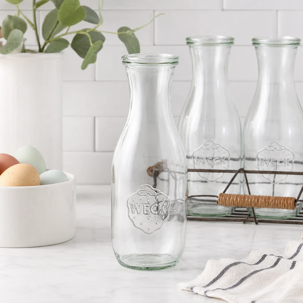 WECK Saftflasche 1062ml Glasflasche leer in moderner weißer Küche mit Eierschale Drahtkorb und Pflanze