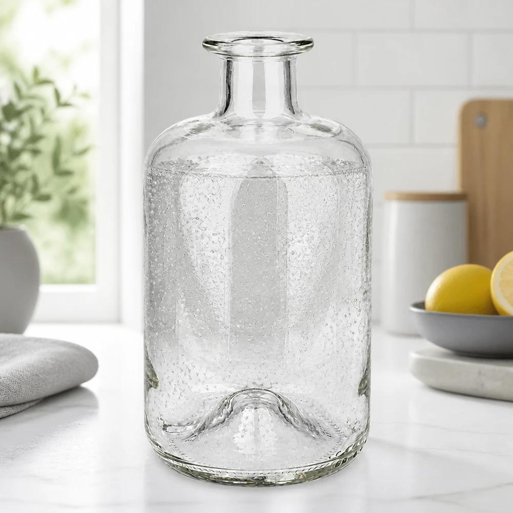 500ml Glasflasche "Luna" ohne Verschluss UNiTWIST Apothekerflasche Luna 500ml mit Bubble-Textur auf weißer Küchenarbeitsplatte neben Zitronen und Pflanzen