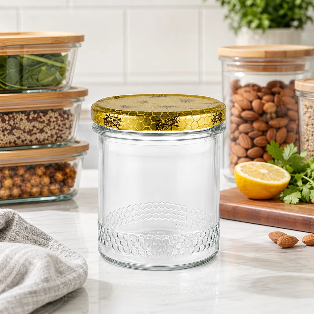 560g Honigglas + BasicSeal Deckel Bienenwabe UNiTWIST 400ml Honigglas mit goldenem Bienenwaben-Deckel auf Küchenarbeitsplatte, Vorratsgläser mit Nüssen im Hintergrund