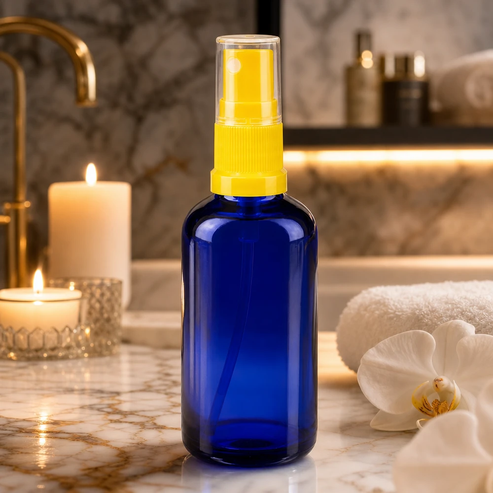 50ml Blauglasflasche mit gelbem Feinnebel-Zerstäuber auf goldenem Marmorwaschtisch